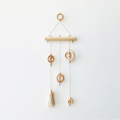 a wooden wind chime hanging on the wall with beads and tassels attached to it