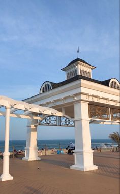 a white gazebo sitting on top of a beach next to the ocean