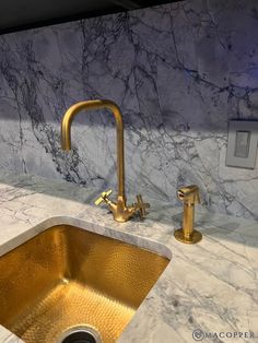 a gold sink and faucet in a white marble countertop with blue lights