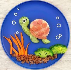 a blue plate topped with different types of vegetables and a turtle made out of food