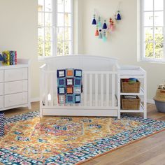 a baby's room with a crib, dresser and rug