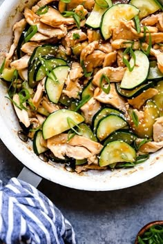 a white bowl filled with cucumbers and chicken