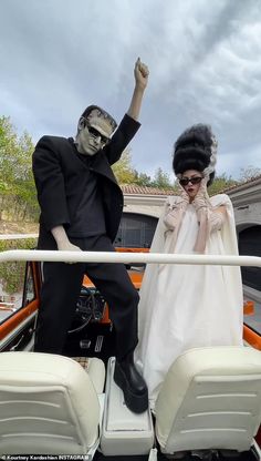 a man and woman dressed up in costumes on a boat with their hands raised to the side