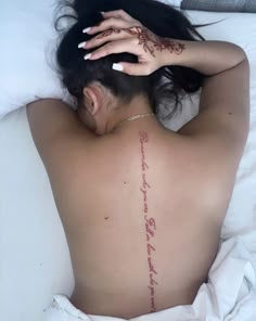 a woman laying in bed with her back turned to the camera and tattoos on her body