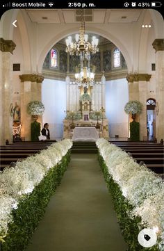 the aisle is lined with white flowers and greenery at the end of the aisle