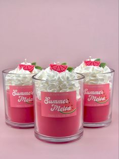 three glass cups filled with whipped cream and topped with green leaves on pink background next to each other