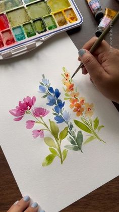 someone is painting flowers with watercolors on paper