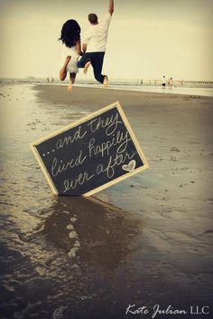 a man and woman jumping in the air with a chalkboard sign attached to them