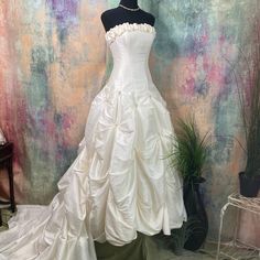 a white wedding dress is on display in front of a wall with flowers and plants