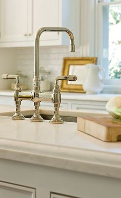 two faucets sitting on top of a kitchen counter next to a cutting board