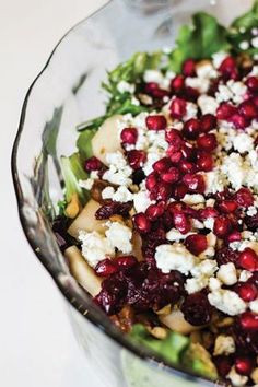 a salad with pomegranates and feta cheese in a glass bowl