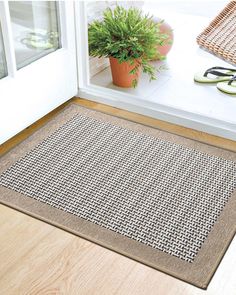 a door mat on the floor next to a potted plant and pair of glasses