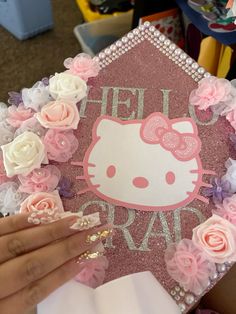 a hello kitty graduation cap with pink and white flowers around the edges that says hello gravy