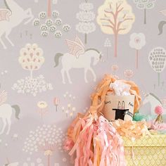 a stuffed animal sitting on top of a basket in front of a wallpapered background