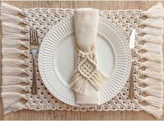 a white plate topped with a tasseled napkin next to a fork and knife