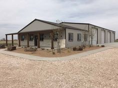 an empty building in the middle of a dirt lot with trees and rocks around it