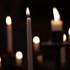 many lit candles are in the dark with one candle on each side and another burning