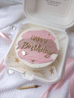 a birthday cake with pink frosting and gold writing on it in a white box