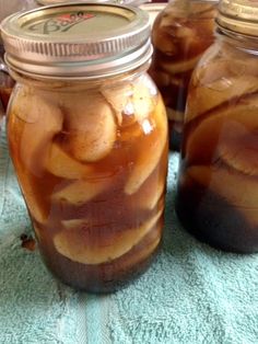 two jars filled with pickles sitting on top of a blue towel next to each other