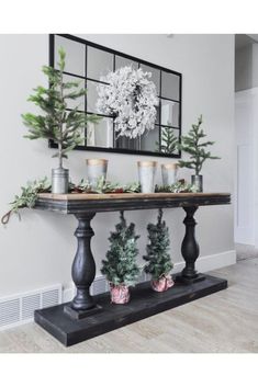 a black table topped with potted plants and greenery on top of a hard wood floor