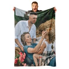 a man holding up a blanket with a photo of two women and a child on it