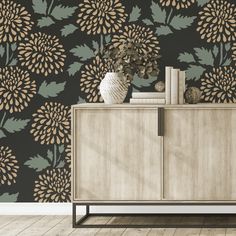 a vase with flowers on top of a wooden cabinet in front of a wallpapered background