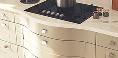 a stove top oven sitting on top of a counter next to drawers and cupboards