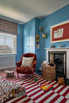 a living room with blue walls, red and white striped rugs and chairs in front of a fire place