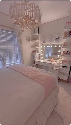 a bedroom with a chandelier hanging from the ceiling and a white bed in front of a window