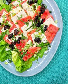 a salad with tomatoes, olives, cheese and lettuce on a plate