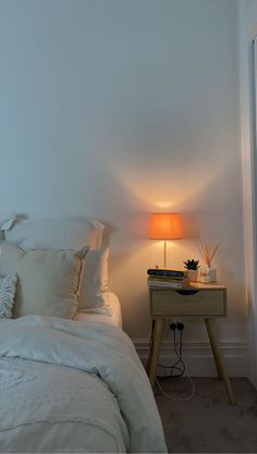 a white bed sitting next to a nightstand with a lamp on it