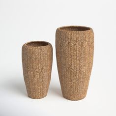 two woven vases sitting next to each other on a white surface with no one around them