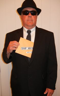 a man in a suit and hat holding up a sign