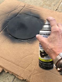 a man is spray painting a hole in the ground with black paint on it's surface