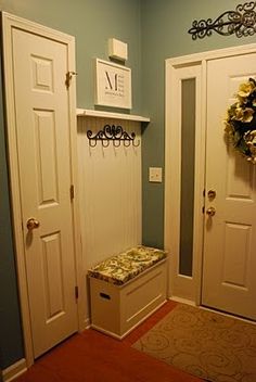 two white doors in a blue room with a bench next to them and a wreath on the wall