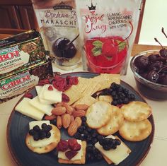 a plate full of crackers, fruit and nuts on a table next to some snacks