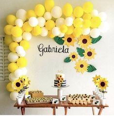 a dessert table with sunflowers, cupcakes and cake on it in front of a sign that says gabrila