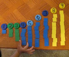 a child's hand is touching the numbers on a bulletin board with construction paper