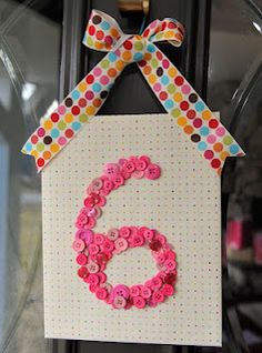 a door hanger decorated with buttons and a number 6 hanging from it's side