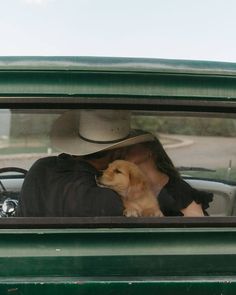 a dog is sitting in the driver's seat of a green truck with his owner