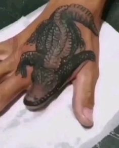 a person's foot with a lizard tattoo on it and a towel in the foreground