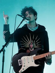 a man holding a guitar while standing in front of a microphone