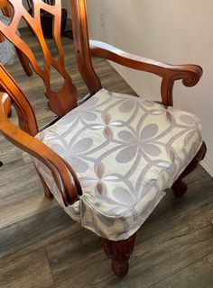 a wooden chair with a patterned seat cover on it's back and armrests