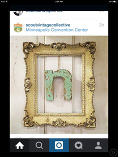 an old gold frame with a green letter on it