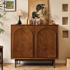 a wooden cabinet in a living room with pictures on the wall