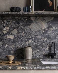 a kitchen counter top with a sink and bowl on it, next to a painting