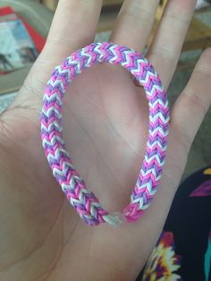 a hand holding a pink and white bracelet