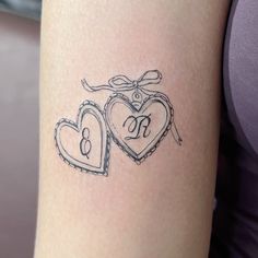 two heart shaped tattoos on the back of a woman's arm