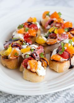 a white plate topped with mini sandwiches covered in toppings