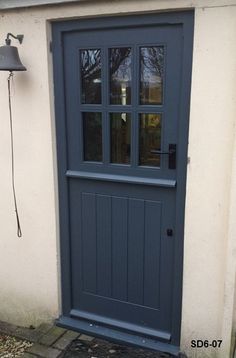 a blue front door with two sidelights and a lamp on the outside of it